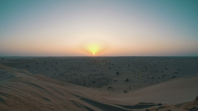 Sun rising over barren dunes timelapse
