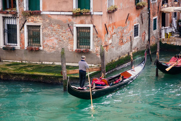 Fototapeta na wymiar man in gondola in narrow canal with bridge Venice, Italy, Europe