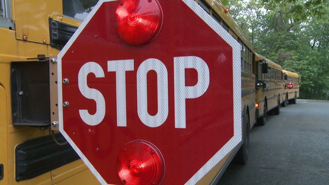Bus stop sign with hazard lights on.
