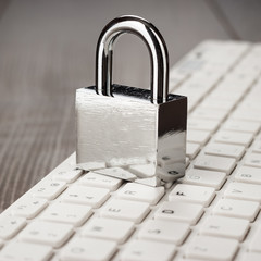 padlock and white computer keyboard on the wooden office table