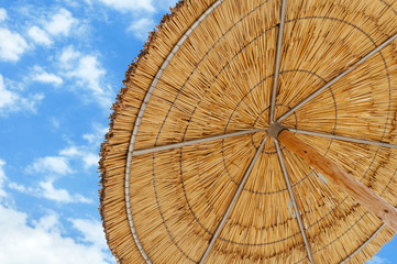 A reed sun umbrella and blue sky symbolizing vacationing in summ