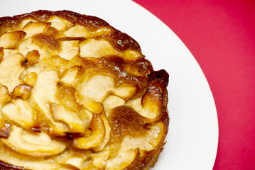 Apple pie on a white plate with red background