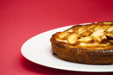 Apple pie on a white plate with red background