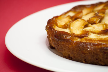 Apple pie on a white plate with red background
