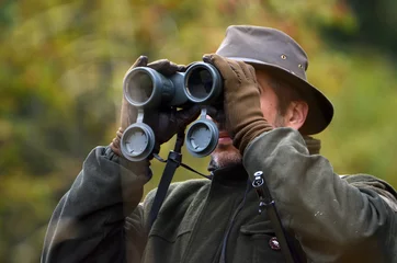 Foto auf Acrylglas Jagd Jäger, der durch ein Fernglas schaut