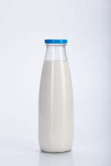 Glass milk bottle with blue cap on a white background