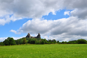 Fototapeta na wymiar Green grassfield with medieval castle ruins under cloudy sky