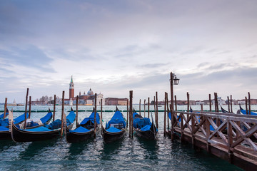 A row of gondolas parked beside the Riva degli Schiavoni in Venice, Italy