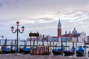 A row of gondolas parked beside the Riva degli Schiavoni in Venice, Italy