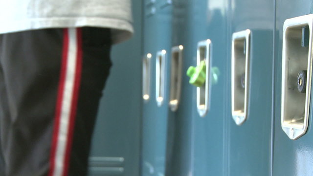 Close up of locker combination and student kicking locker closed