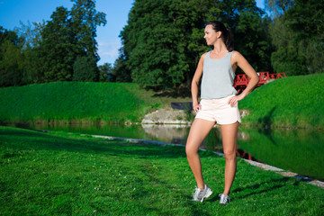 young slim woman in sportswear posing in park