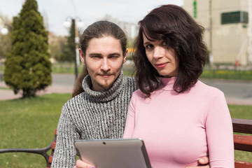 Trendy young students couple in town using tablet