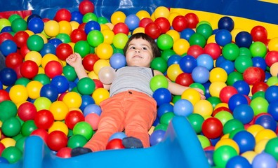 Fototapeta na wymiar Мальчик играется в разноцветных шариках