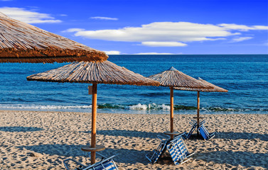 Sunbed, straw umbrella on beautiful beach background