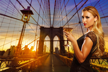Blond girl cheers with vermout cup in NYC sunset