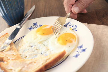 A man with a plate of fried eggs and buttered toast