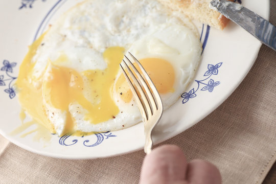 A man is ready to eat his morning meal of runny fried eggs with buttered toast.