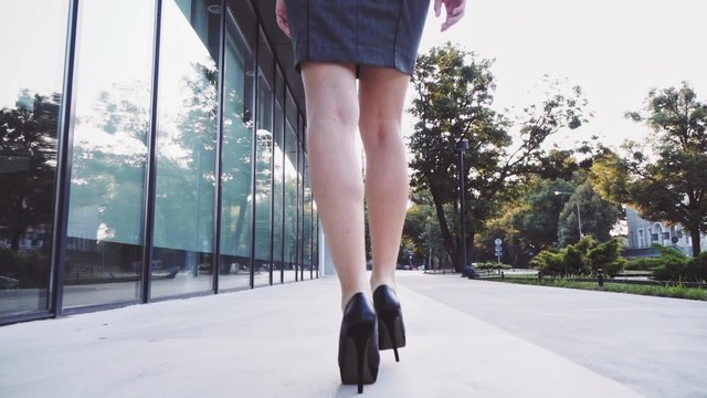 Sexy woman legs in black high heels shoes walking in the city urban street. Steadicam stabilized shot, Slow motion. Lens flare. Female legs in high-heeled shoes in the morning. Cinematic shot. 