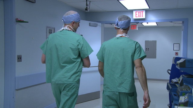 Doctors converse as they walk through hallway