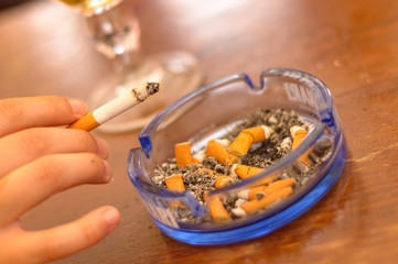 Hand holding cigarette over an ashtray