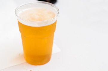 Soft focus plastic glass of beer on a white table