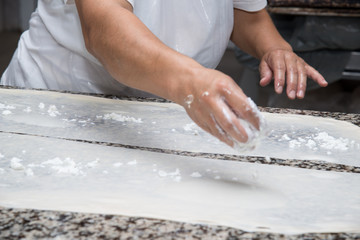 close up of female hands kneading dough and making banitsa