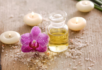 wooden background –pink orchid , candle, oil and pile of salt