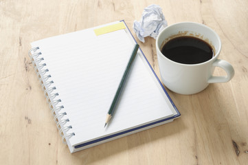 Notebook and coffee on wooden background.