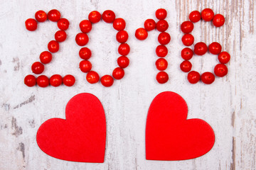New year 2016 made of red viburnum and red wooden hearts on old wooden background
