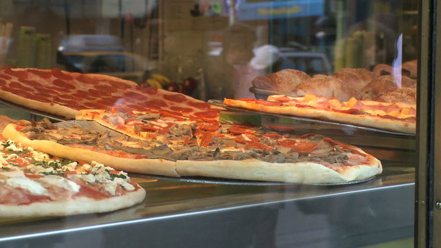 Reflections of People walking by a Pizzeria