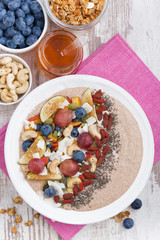 oatmeal with assorted fresh fruits, nuts and chia, vertical