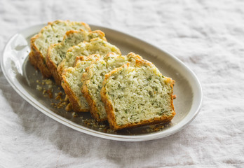 cake with cheese and herbs on an oval plate on a light surface