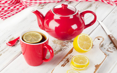 Teapot and cups with lemon on wooden table.