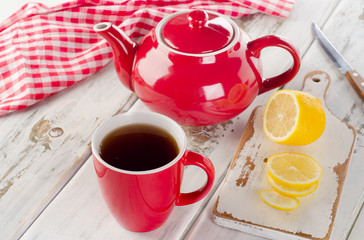 Teapot and cups with lemon on a white wooden table.