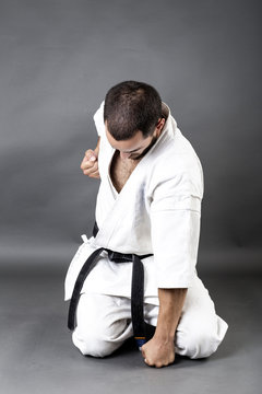 portrait of young man in white kimono and black belt training ma