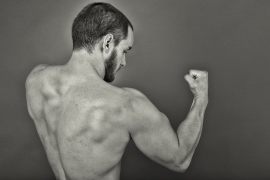 Back view of muscular young man showing his muscles