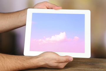 Hands holding tablet PC with sky in screen. Cloud computing concept