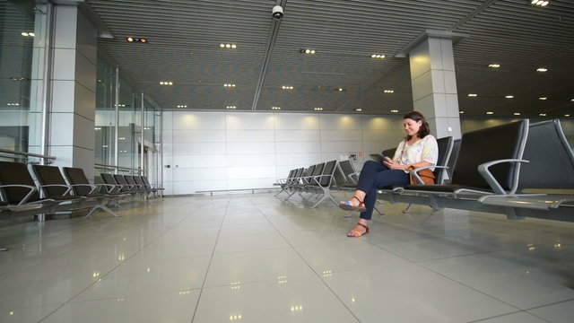 Young woman using a digital tablet in airport waiting area