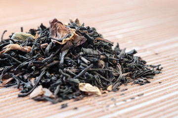 Dry tea leaves spread on light brown color background