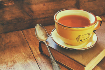 Obraz premium Cup of tea wit old book h autumn leaves and a warm scarf on wooden table 