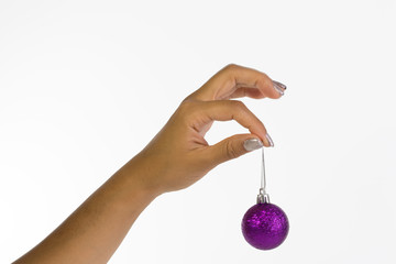 Woman's hand with silver nails holding a purple christmas bauble