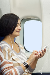 Fototapeta premium caucasian woman passenger in airplane using mobile smart device with headphones
