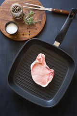 Raw pork rib chops on the grill frying pan with spices and herbs