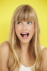 Excited young woman looking away on yellow