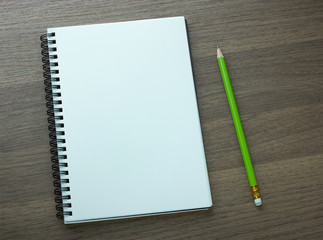 blank spiral notebook and pencil on dark wood background