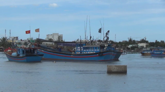 Blue Vietnamese ships moored on the river. red flags are developed in the wind.
