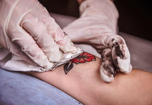 Tattooer showing process of making tattoo