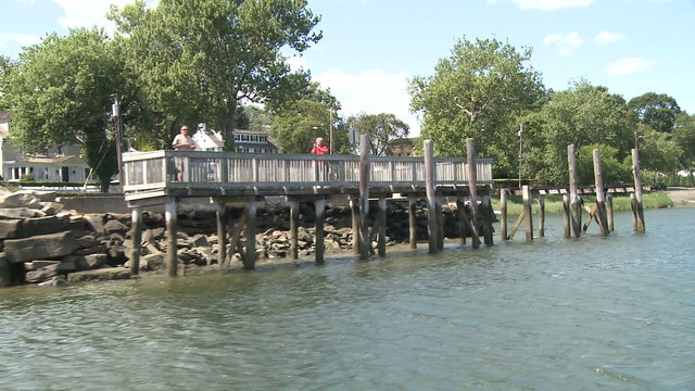 Two people on a dock watching the boats go by.