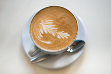 Cappuchino or latte coffe in a white cup on a light background