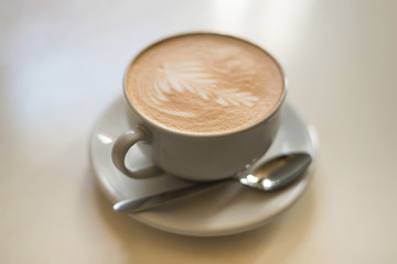 Cappuchino or latte coffe in a white cup on a light background